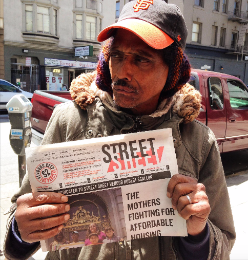 A vendor holding a copy of the Street Sheet